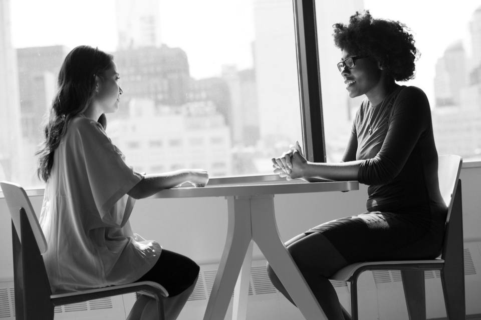 Two people talking across a table during a rental screening conversation